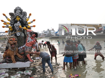 Devotees prepare an idol of the Hindu goddess Durga for its immersion into the Hooghly River in Kolkata, India, on October 13, 2024. The ann...