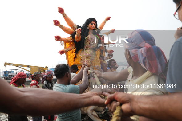 Devotees prepare an idol of the Hindu goddess Durga for its immersion into the Hooghly River in Kolkata, India, on October 13, 2024. The ann...