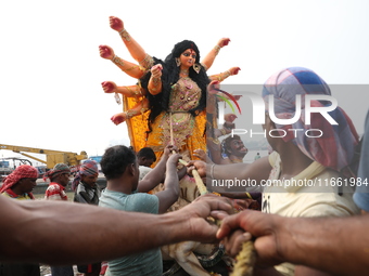 Devotees prepare an idol of the Hindu goddess Durga for its immersion into the Hooghly River in Kolkata, India, on October 13, 2024. The ann...