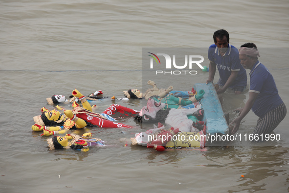 Devotees immerse an idol of the Hindu goddess Durga into the Hooghly River in Kolkata, India, on October 13, 2024. The annual Durga Puja fes...