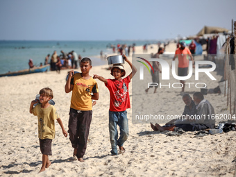 Displaced Palestinian boys walk back to their family's tents at a makeshift camp on the beach of Deir al-Balah, central Gaza Strip, on Octob...