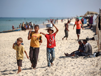 Displaced Palestinian boys walk back to their family's tents at a makeshift camp on the beach of Deir al-Balah, central Gaza Strip, on Octob...