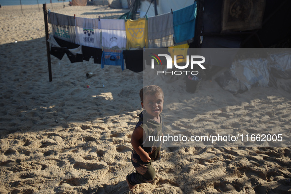 A displaced Palestinian boy walks outside his tent at a makeshift camp on the beach of Deir al-Balah in the central Gaza Strip on October 13...