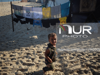 A displaced Palestinian boy walks outside his tent at a makeshift camp on the beach of Deir al-Balah in the central Gaza Strip on October 13...