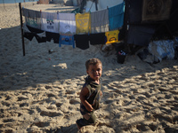 A displaced Palestinian boy walks outside his tent at a makeshift camp on the beach of Deir al-Balah in the central Gaza Strip on October 13...