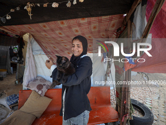 A displaced Palestinian carries her pet cat near a makeshift camp, housing displaced Palestinians, on the beach of Deir al-Balah, central Ga...