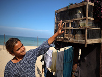 A displaced Palestinian girl plays with a bird outside her displaced family's tent at a makeshift camp on the beach of Deir al-Balah, centra...