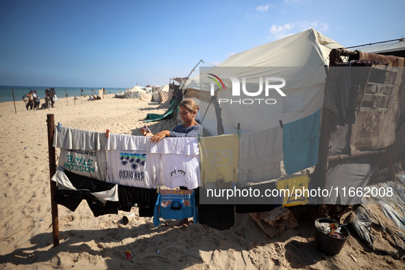 A displaced Palestinian girl hangs clothes outside her displaced family's tent at a makeshift camp on the beach of Deir al-Balah, central Ga...