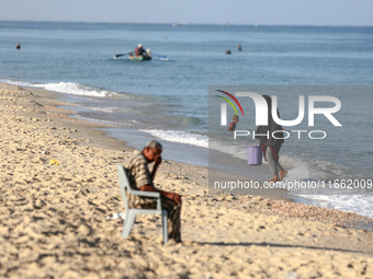 A displaced Palestinian transports a bucket of sea water on the beach of Deir al-Balah in the central Gaza Strip on October 13, 2024, amid t...