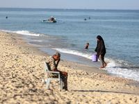 A displaced Palestinian transports a bucket of sea water on the beach of Deir al-Balah in the central Gaza Strip on October 13, 2024, amid t...