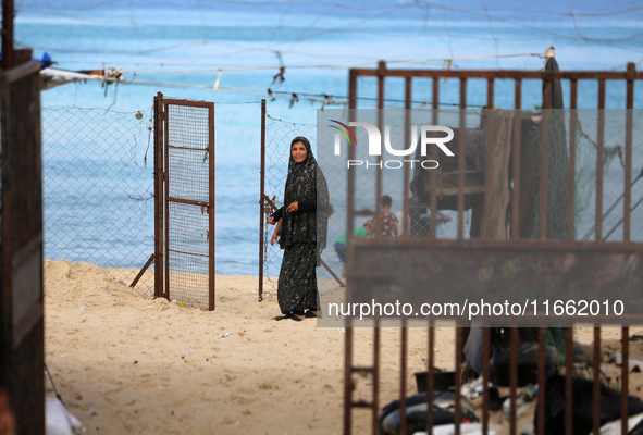 A displaced Palestinian woman stands outside her tent at a makeshift camp on the beach of Deir al-Balah, central Gaza Strip, on October 13,...