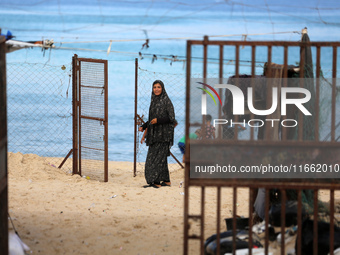 A displaced Palestinian woman stands outside her tent at a makeshift camp on the beach of Deir al-Balah, central Gaza Strip, on October 13,...