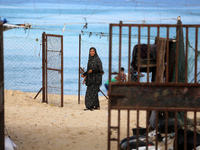 A displaced Palestinian woman stands outside her tent at a makeshift camp on the beach of Deir al-Balah, central Gaza Strip, on October 13,...