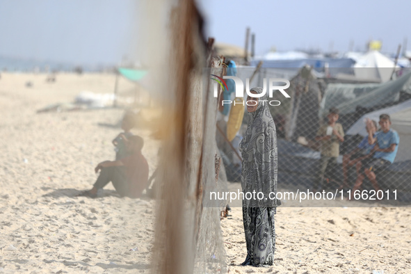 A displaced Palestinian woman stands outside her tent at a makeshift camp on the beach of Deir al-Balah, central Gaza Strip, on October 13,...