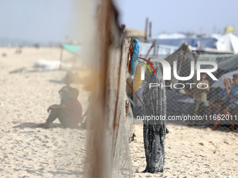 A displaced Palestinian woman stands outside her tent at a makeshift camp on the beach of Deir al-Balah, central Gaza Strip, on October 13,...