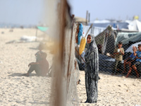 A displaced Palestinian woman stands outside her tent at a makeshift camp on the beach of Deir al-Balah, central Gaza Strip, on October 13,...