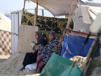 Displaced Palestinians sit outside their tent at a makeshift camp on the beach of Deir al-Balah in the central Gaza Strip on October 13, 202...