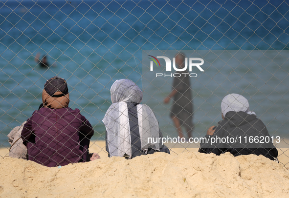 Displaced Palestinians sit outside their tent at a makeshift camp on the beach of Deir al-Balah in the central Gaza Strip on October 13, 202...