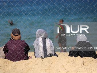 Displaced Palestinians sit outside their tent at a makeshift camp on the beach of Deir al-Balah in the central Gaza Strip on October 13, 202...