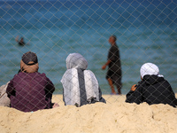 Displaced Palestinians sit outside their tent at a makeshift camp on the beach of Deir al-Balah in the central Gaza Strip on October 13, 202...