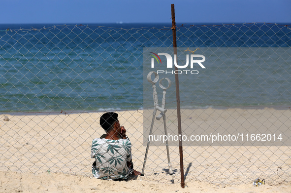 A displaced injured Palestinian sits outside his tent at a makeshift camp on the beach of Deir al-Balah, central Gaza Strip, on October 13,...