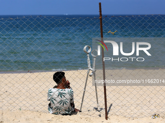 A displaced injured Palestinian sits outside his tent at a makeshift camp on the beach of Deir al-Balah, central Gaza Strip, on October 13,...