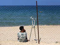 A displaced injured Palestinian sits outside his tent at a makeshift camp on the beach of Deir al-Balah, central Gaza Strip, on October 13,...