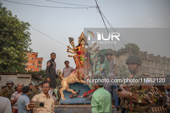 Bangladeshi Hindu devotees immerse an idol of their deity Durga into the Buriganga River during celebrations on the last day of the Durga Pu...