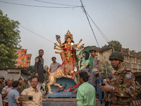 Bangladeshi Hindu devotees immerse an idol of their deity Durga into the Buriganga River during celebrations on the last day of the Durga Pu...