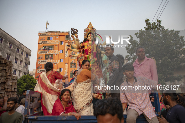 Bangladeshi Hindu devotees immerse an idol of their deity Durga into the Buriganga River during celebrations on the last day of the Durga Pu...