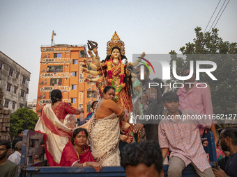 Bangladeshi Hindu devotees immerse an idol of their deity Durga into the Buriganga River during celebrations on the last day of the Durga Pu...