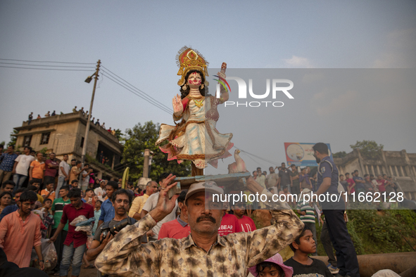 Bangladeshi Hindu devotees immerse an idol of their deity Durga into the Buriganga River during celebrations on the last day of the Durga Pu...