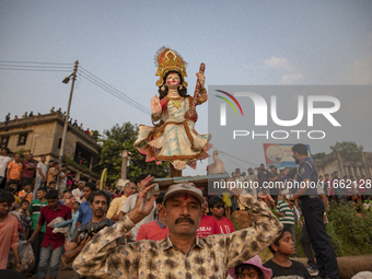 Bangladeshi Hindu devotees immerse an idol of their deity Durga into the Buriganga River during celebrations on the last day of the Durga Pu...