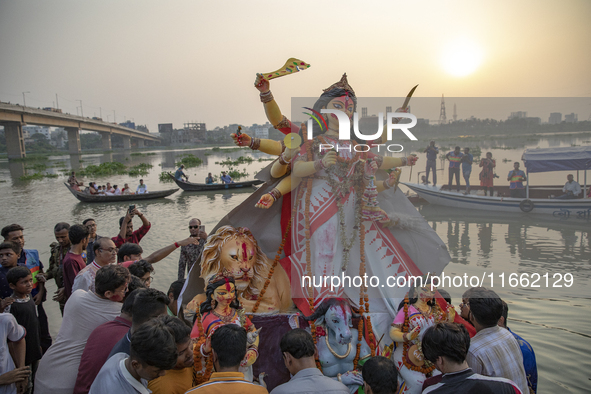 Bangladeshi Hindu devotees immerse an idol of their deity Durga into the Buriganga River during celebrations on the last day of the Durga Pu...