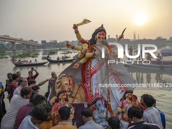 Bangladeshi Hindu devotees immerse an idol of their deity Durga into the Buriganga River during celebrations on the last day of the Durga Pu...