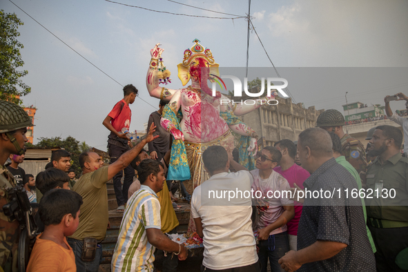 Bangladeshi Hindu devotees immerse an idol of their deity Durga into the Buriganga River during celebrations on the last day of the Durga Pu...