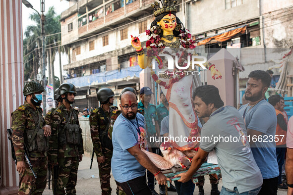 Bangladesh Army officers stand nearby to secure the area as Bangladeshi Hindu devotees immerse an idol of their deity Durga into the Burigan...