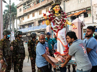 Bangladesh Army officers stand nearby to secure the area as Bangladeshi Hindu devotees immerse an idol of their deity Durga into the Burigan...