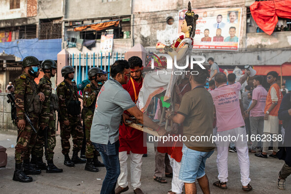 Bangladesh Army officers stand nearby to secure the area as Bangladeshi Hindu devotees immerse an idol of their deity Durga into the Burigan...