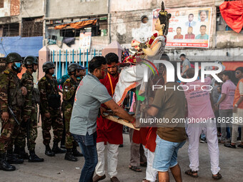 Bangladesh Army officers stand nearby to secure the area as Bangladeshi Hindu devotees immerse an idol of their deity Durga into the Burigan...