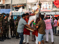 Bangladesh Army officers stand nearby to secure the area as Bangladeshi Hindu devotees immerse an idol of their deity Durga into the Burigan...