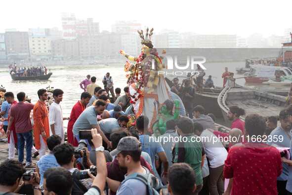 Bangladeshi Hindu devotees immerse an idol of their deity Durga into the Buriganga River during the last day of the Durga Puja, the largest...