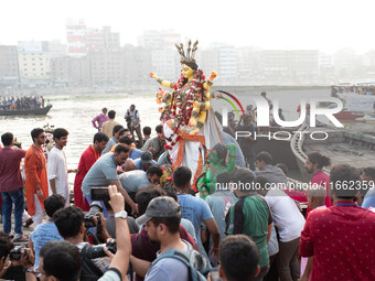 Bangladeshi Hindu devotees immerse an idol of their deity Durga into the Buriganga River during the last day of the Durga Puja, the largest...