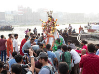 Bangladeshi Hindu devotees immerse an idol of their deity Durga into the Buriganga River during the last day of the Durga Puja, the largest...