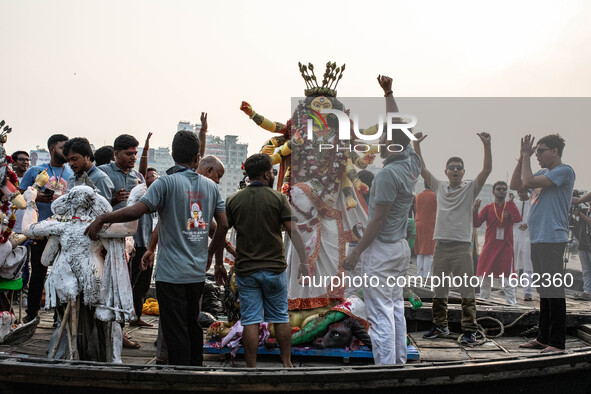 Bangladeshi Hindu devotees immerse an idol of their deity Durga into the Buriganga River during the last day of the Durga Puja, the largest...