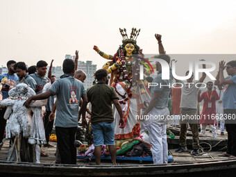 Bangladeshi Hindu devotees immerse an idol of their deity Durga into the Buriganga River during the last day of the Durga Puja, the largest...