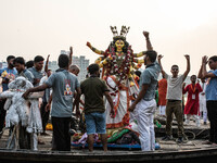 Bangladeshi Hindu devotees immerse an idol of their deity Durga into the Buriganga River during the last day of the Durga Puja, the largest...