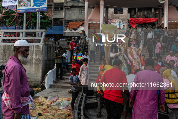 Bangladeshi Hindu devotees immerse an idol of their deity Durga into the Buriganga River during the last day of the Durga Puja, the largest...