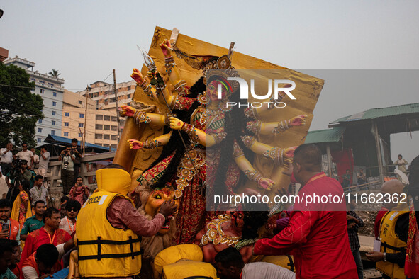 Bangladeshi Hindu devotees immerse an idol of their deity Durga into the Buriganga River during the last day of the Durga Puja, the largest...