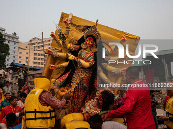 Bangladeshi Hindu devotees immerse an idol of their deity Durga into the Buriganga River during the last day of the Durga Puja, the largest...